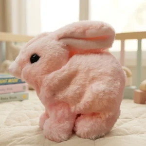 Soft pink plush bunny rabbit toy sitting on a quilted bed surface.