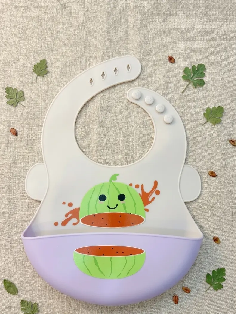 Light gray and pastel lavender waterproof silicone baby bib featuring a cute smiling watermelon print and adjustable neck buttons.